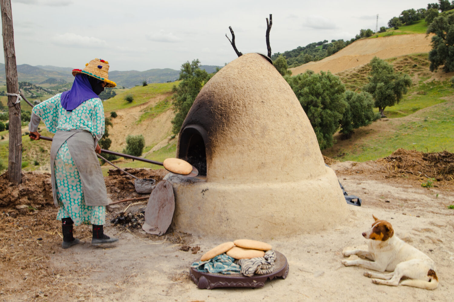 Berber woman baking traditional Moroccan bread in a clay oven
