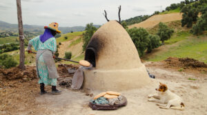 Berber woman baking traditional Moroccan bread in a clay oven