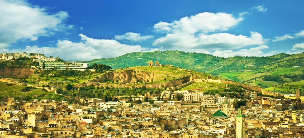 Panoramic view of Fes, Morocco with the historic medina, city walls, and green hills