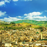 Panoramic view of Fes, Morocco with the historic medina, city walls, and green hills