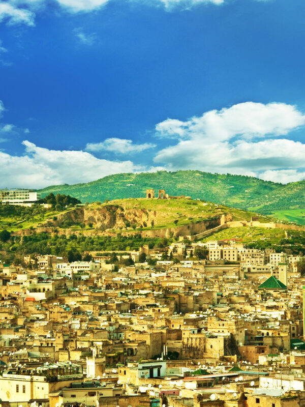Panoramic view of Fes, Morocco with the historic medina, city walls, and green hills