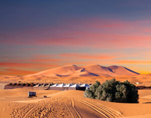Luxury desert camp in Merzouga dunes at sunset