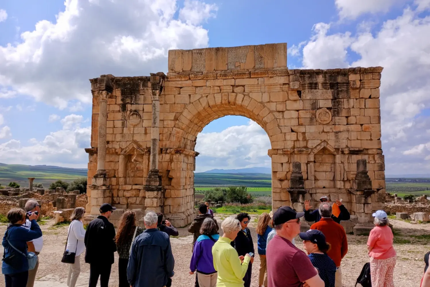 Ancient Roman entrance gate in Volubilis Morocco with tourists on 10 Day Private Morocco Tour from Casablanca