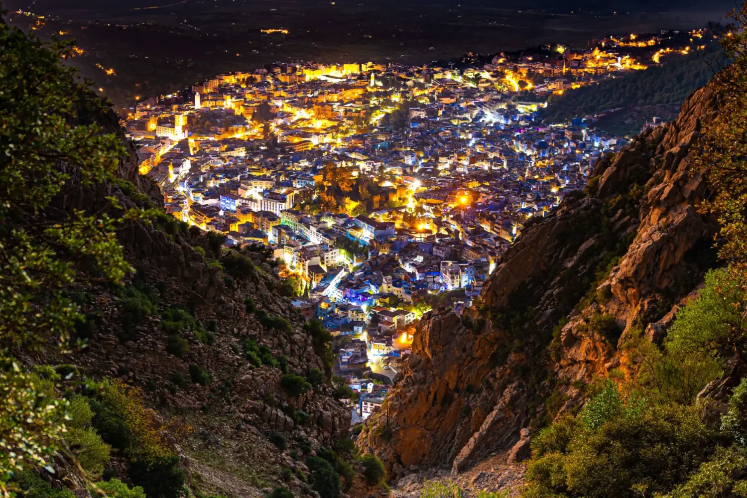 Evening panoramic view of Chefchaouen with bright city lights in the Rif Mountains