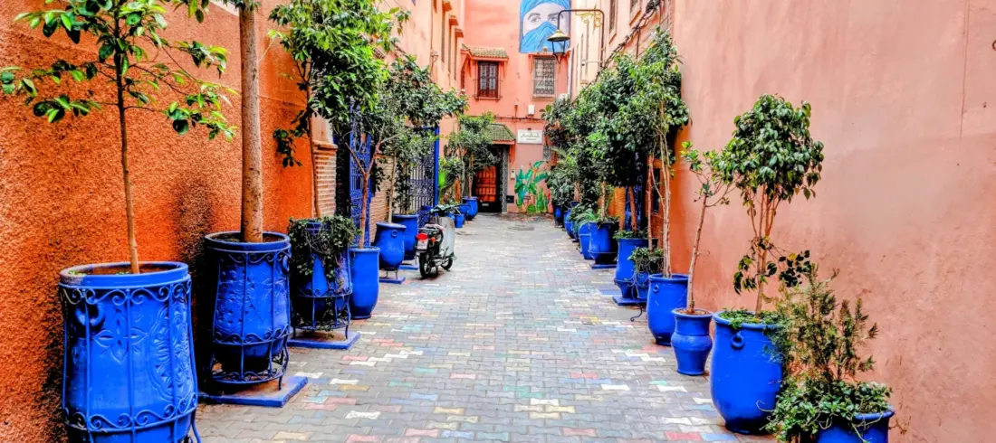Colorful Marrakech street with blue pots and local shops.
