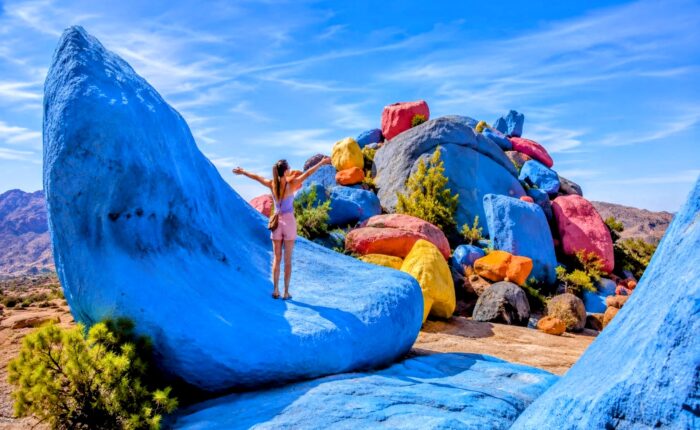 Tourist enjoying the colorful painted rocks near Tafraoute in Morocco's Anti-Atlas Mountains visited during the 30 Day Morocco Explorer Tour from Casablanca.