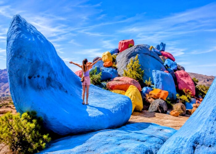 Tourist enjoying the colorful painted rocks near Tafraoute in Morocco's Anti-Atlas Mountains visited during the 30 Day Morocco Explorer Tour from Casablanca.